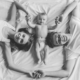 Top view of young parents and their baby holding hands looking at camera and smiling while lying together on bed